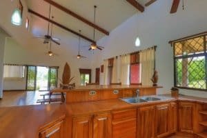 Open-concept kitchen and living room in a Costa Rican home with high ceilings and large windows.