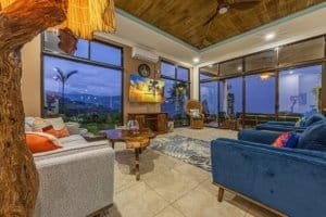 Spacious living room with large windows overlooking the ocean and lush garden.