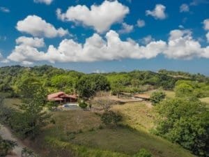 Scenic view of a hacienda-style home with stables and lush greenery in Dominical.