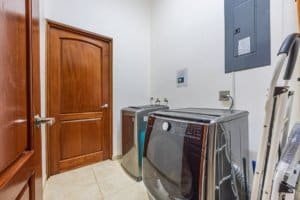 Laundry room with washing machine, dryer, and utility sink in Costa Rica home.