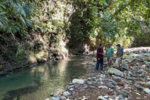 Group of people examining river and rocks in Costa Rica rainforest.