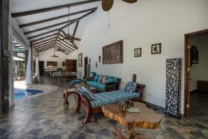 Spacious living room with high vaulted ceiling, tropical decor, and pool view in Dominical.