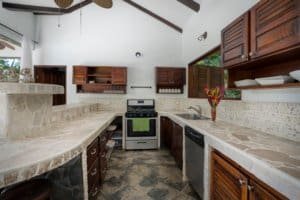 Rustic kitchen with stone countertops, wooden cabinets, and modern appliances in Costa Rica.