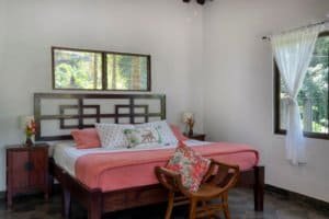 Comfortable bedroom with pink bedding, wooden furniture, and tropical views.