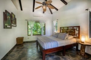 Interior of a Bali style bedroom with wooden furniture and ceiling fan in Dominical.