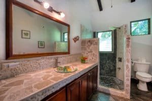 Interior of a Bali style home bathroom with stone accents and natural light.