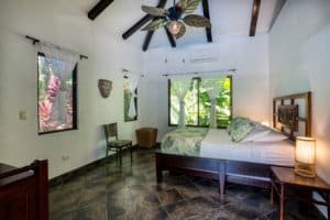 Cozy Bali style bedroom with ceiling fan and tropical views in Dominical.