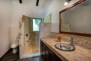 Bathroom in Costa Rica with stone accents, shower, and vanity with mirror.