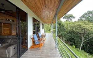 Balcony with chairs overlooking lush green mountain scenery in Dominical.