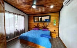 Bedroom with wooden walls, mountain view window, and colorful decor.