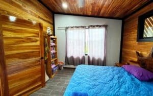 Interior of a wooden bedroom with a large bed and mountain view window.