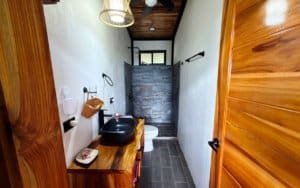 Small bathroom with wooden accents, sink, and toilet near mountain views.