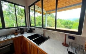 Modern kitchen with large windows overlooking lush green mountains in Dominical.