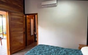 Bedroom with air conditioning, wooden door, and mountain view in Dominical.