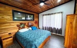 Comfortable bedroom with wooden walls and mountain view window.