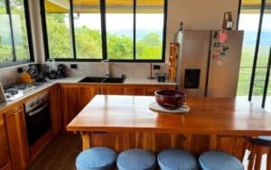 Kitchen with wooden cabinets, large windows, and mountain scenery in the background.