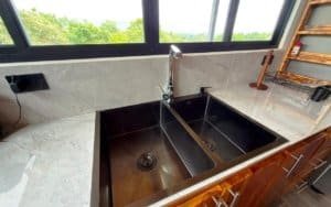 Contemporary kitchen with black sink and mountain view through large windows.