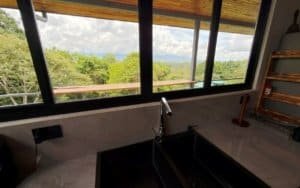 Living room with large windows showing lush mountain views in Costa Rica.