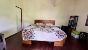 Bedroom with wooden bed, quilted blanket, and simple furnishings in a cozy Costa Rica home.