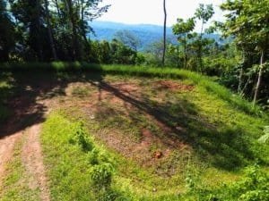 Elevated ocean view cleared land with surrounding jungle and distant hills.