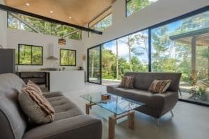 Bright modern living room with large glass doors opening to lush greenery in Dominical, Costa Rica.