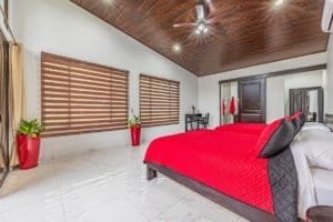 Bedroom with red bedspread and large windows in a bright, modern villa.