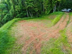 Dominical real estate: cleared elevated land with surrounding jungle and distant cars in a gravel or.