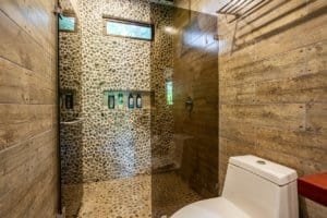 Stone and wood bathroom with pebble shower and rustic finishes.