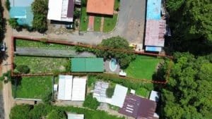 Aerial view of a residential property with a rectangular plot, pool, surrounding homes, and wooded背景.