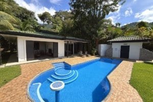 Panoramic ocean view villa with a curved pool, surrounding patio, and lush tropical landscaping.