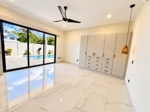 Bright living space with large sliding glass doors to pool, white marble floors, ceiling fan, and a@.