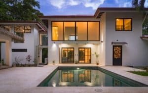 Modern tropical villa with private pool and glass doors at dusk.