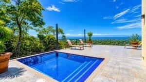 Panoramic ocean view from terrace with blue pool and seating area.