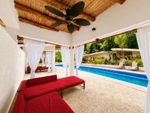 Poolside condo with garden view, white curtains, and tropical surroundings.