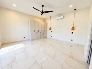 Bright spacious room with white marble floor, built-in storage, ceiling fan and pendant lights.