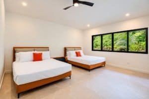Two queen beds in a bright Costa Rica room with large window showing lush greenery.