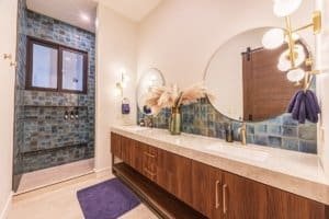 Modern bathroom with double sinks, blue tile accents, and round mirror in a Costa Rica villa.