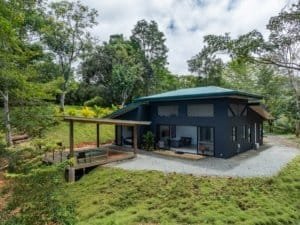 Creekside modern home in Costa Rica with covered patio and surrounding trees.