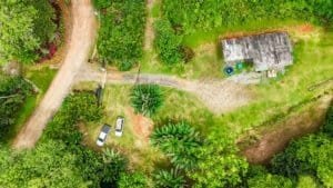 Aerial view of lush green property with a small building and vehicles in Dominical.