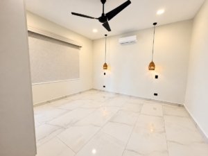Bright empty living room with large marble floor, ceiling fan, pendant lights, and wall-mounted AC.