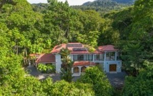 Costa Rica tropical villa with red roof surrounded by lush green forest.