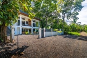 Dominical real estate: ocean view condo property with lush greenery and gravel driveway.