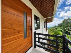 Dominical real estate ocean view balcony with wooden door and lush tropical greenery.