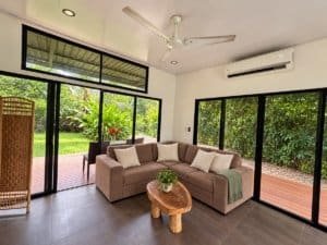 Bright living room with large windows and view of lush garden in Dominical.