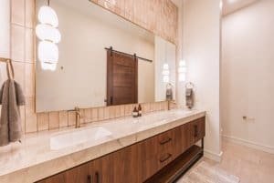 Luxurious bathroom with double sinks, wooden cabinetry, and large mirror.
