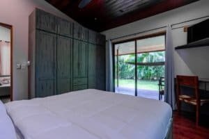 Turn-key coastal home bedroom with large wardrobe and sliding door to garden.