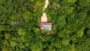 Overhead view of a small house surrounded by dense Costa Rican jungle trees.