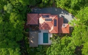 Aerial view of a tropical 2-bedroom modern home with pool and solar panels in Costa Rica.