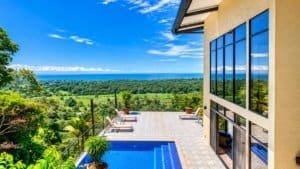 Dominical area hillside home with pool, glass walls and lush greenery overlooking the Pacific Ocean.