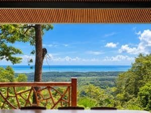 Dominical real estate: panoramic ocean view with lush greenery and distant coastline.
